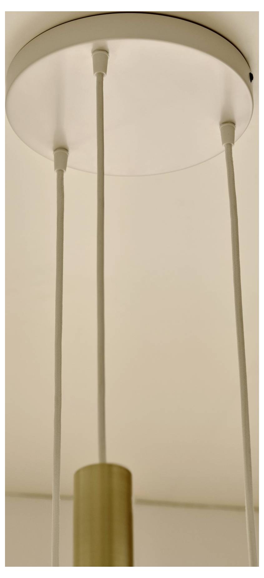 Eine Deckenleuchte mit drei hängenden Schnüren, die mit einer zentralen kreisförmigen Basis verbunden sind, mit modernem und minimalistische Design in einer neutralen Umgebung.