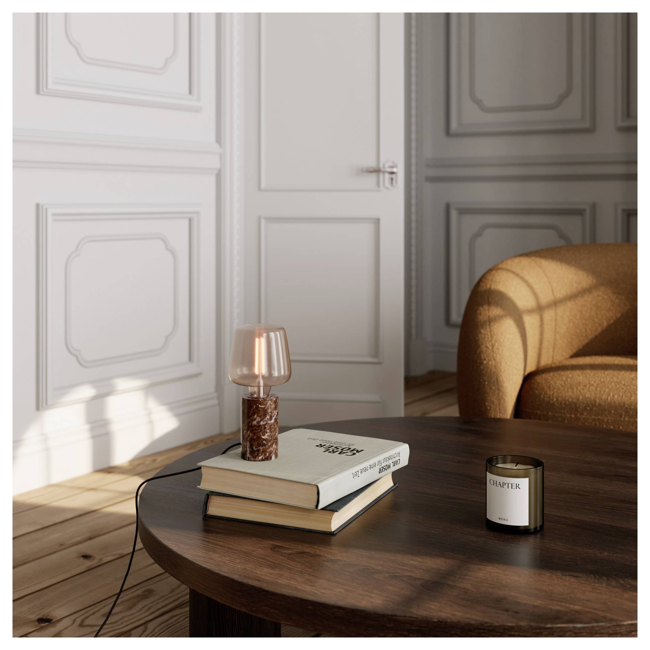 Ein gemütliches Zimmer mit einem Holztisch, zwei übereinander gestapelten Büchern, einer kleinen Lampe und einer Kerze. Sonnenlicht wirft Schatten auf den Hartholzboden und die Wände.