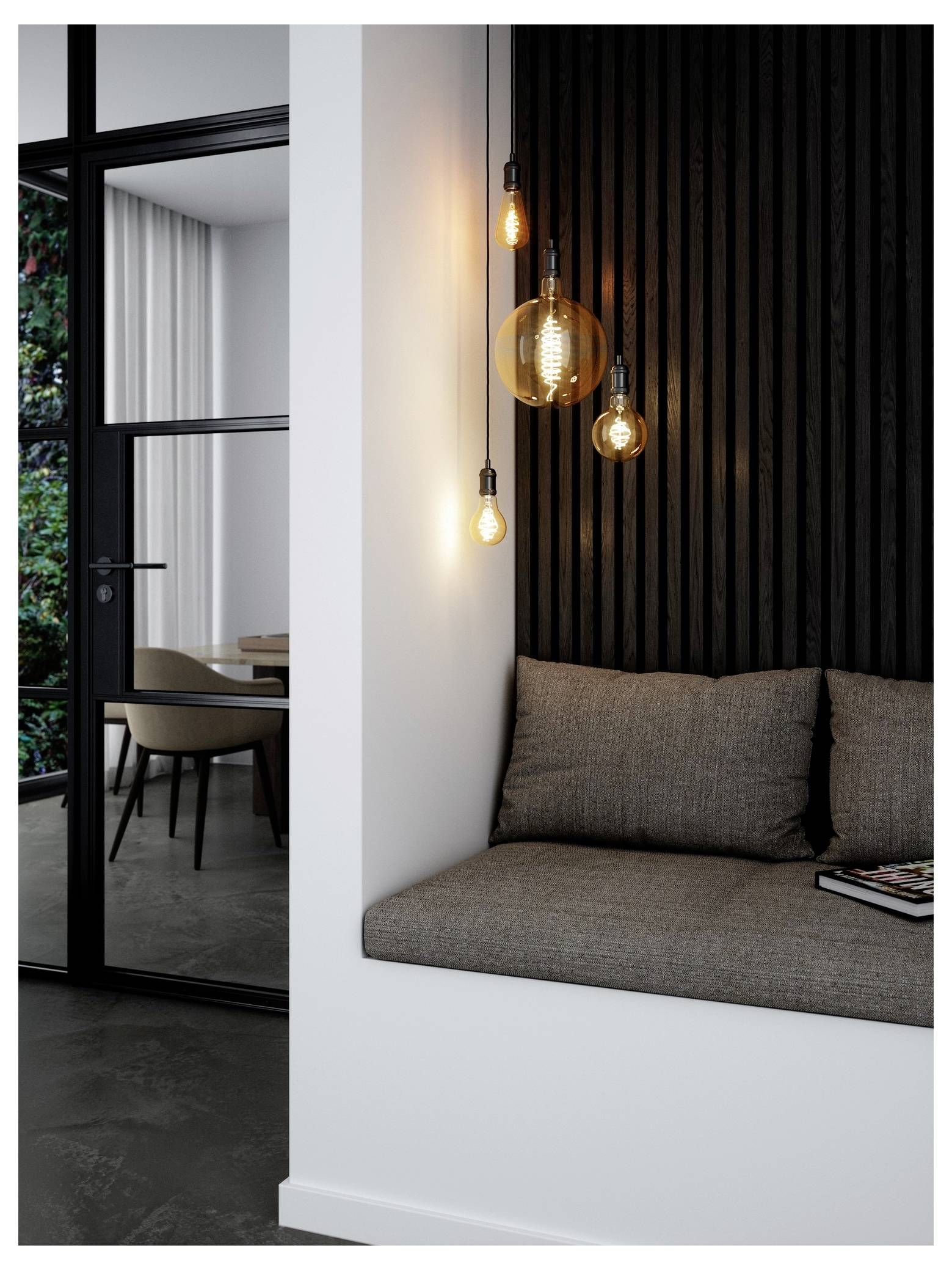 Eine moderne Sitzecke mit grauen Kissen wird von vier freiliegenden Glühbirnen beleuchtet, die in unterschiedlichen Höhen hängen. Ein Tisch und Stühle sind durch eine Glastür in der Nähe sichtbar.