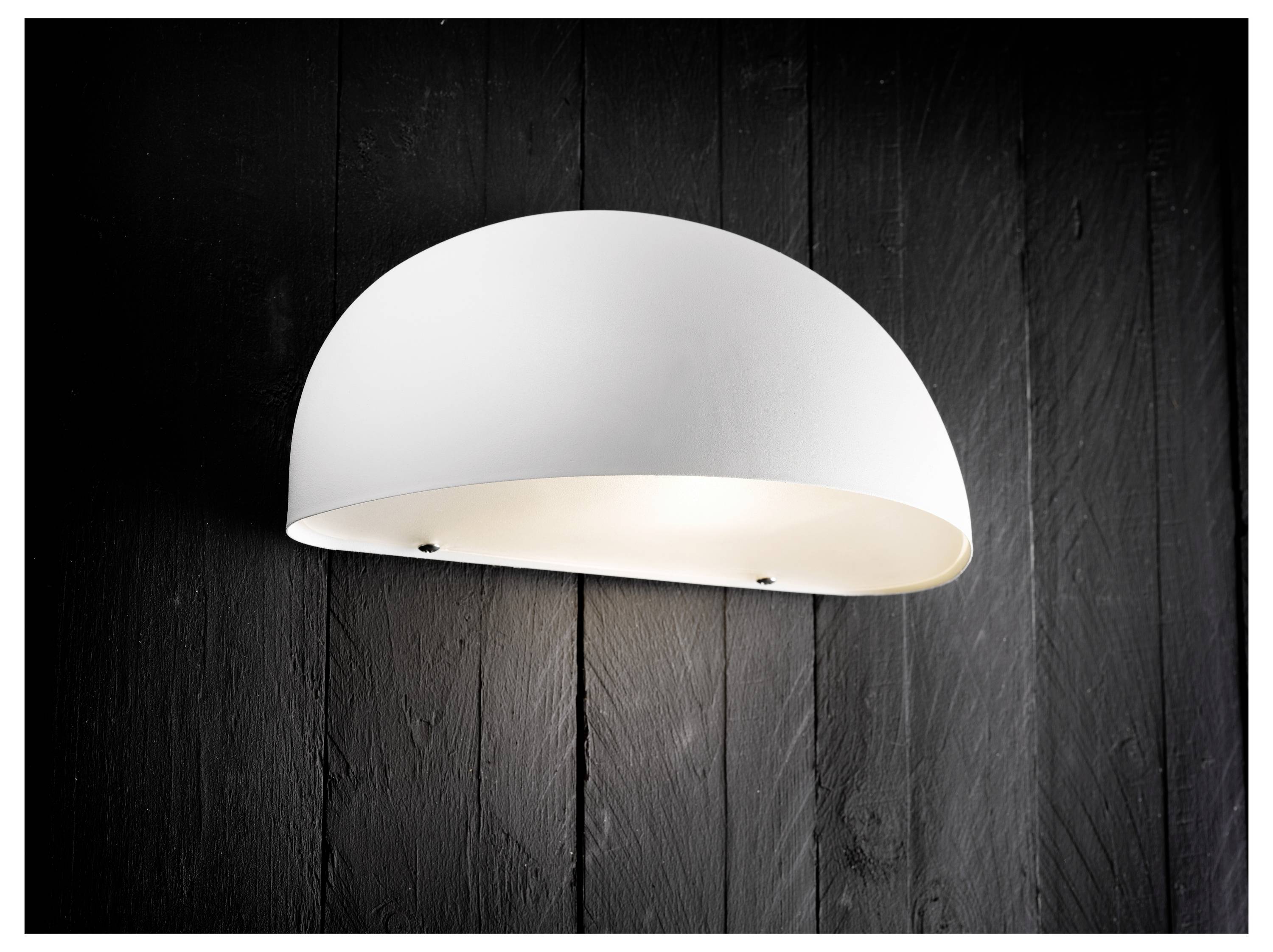 Ein moderner weißer Wandleuchter mit Domform ist an einer strukturierten schwarzen Wand montiert und spendet sanfte, stimmungsvolle Beleuchtung.