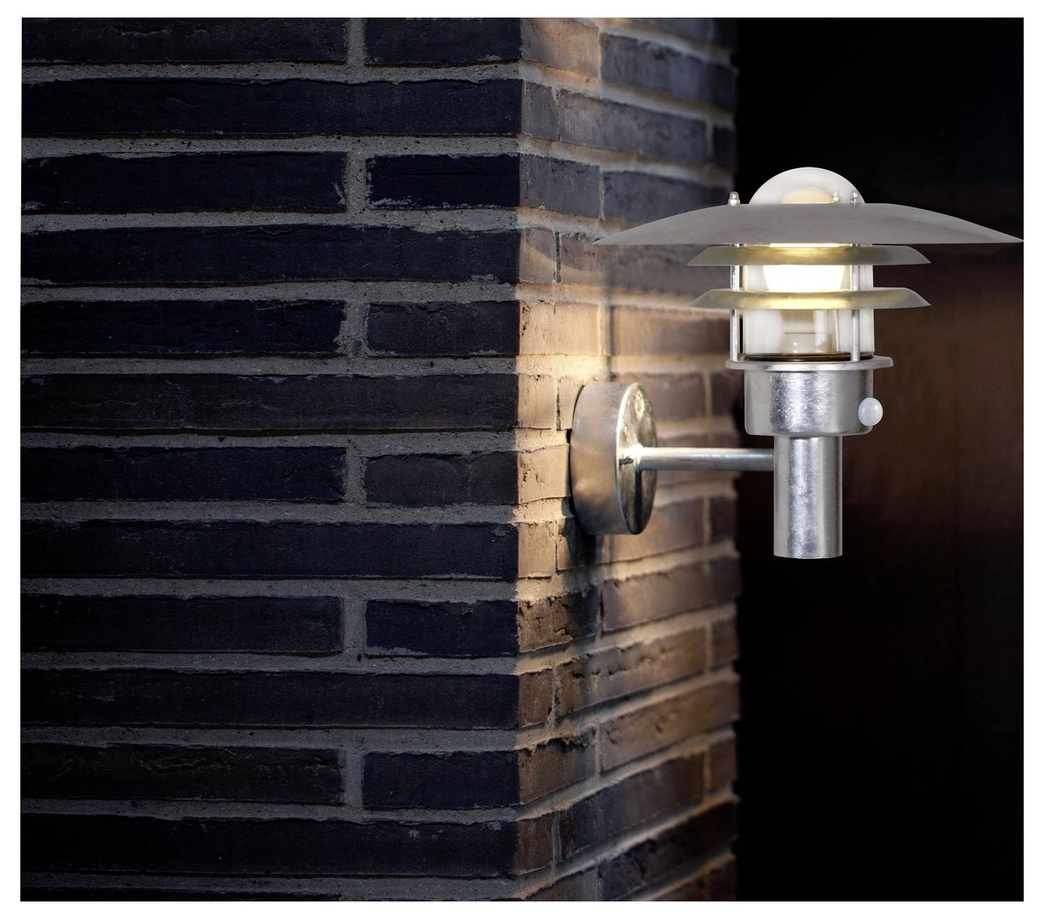 Ein modernes Wandleuchten-Modell mit metallischem Finish beleuchtet eine dunkle Backsteinmauer und wirft einen sanften Glanz.