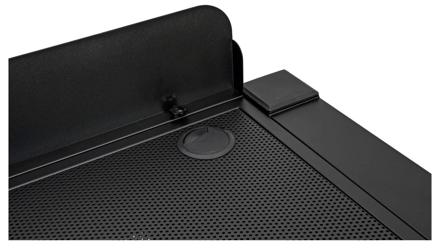 Eine schwarze perforierte Metalloberfläche mit erhöhter Rückseite, mit einem kleinen runden Deckel und einem rechteckigen Abschnitt auf der rechten Seite.