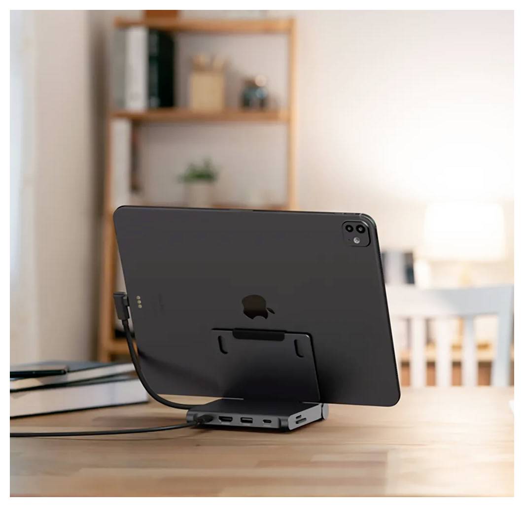 Ein iPad in einem Ständer auf einem Holzschreibtisch, mit Kabel verbunden in einem sanft beleuchteten Heimarbeitsplatz.