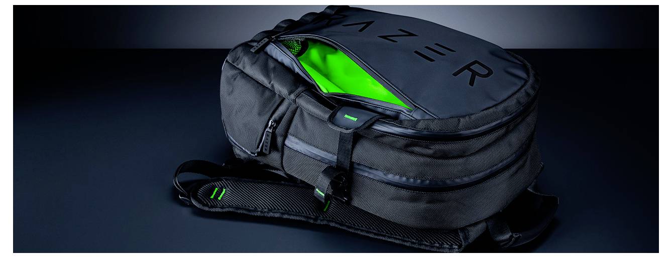 Ein schwarzer Razer-Rucksack mit geöffnetem Hauptfach, das einen leuchtend grünen Innenraum zeigt, auf einer dunklen Oberfläche präsentiert.