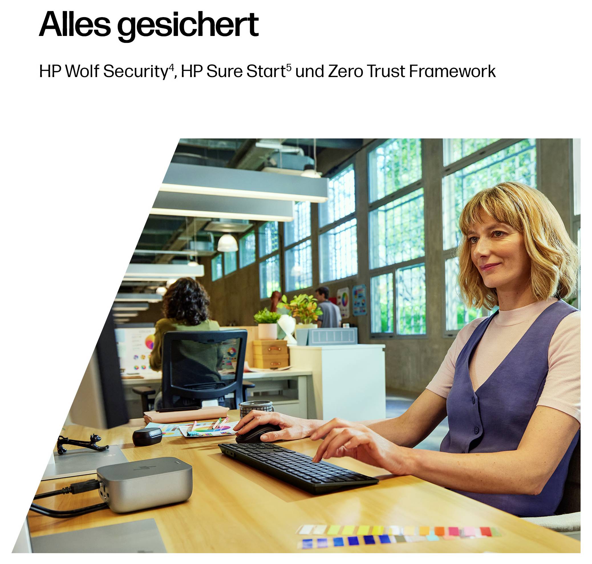 Eine Frau sitzt an einem Schreibtisch in einem modernen Büro und benutzt einen Desktop-Computer. Der Text oben liest sich „Alles gesichert