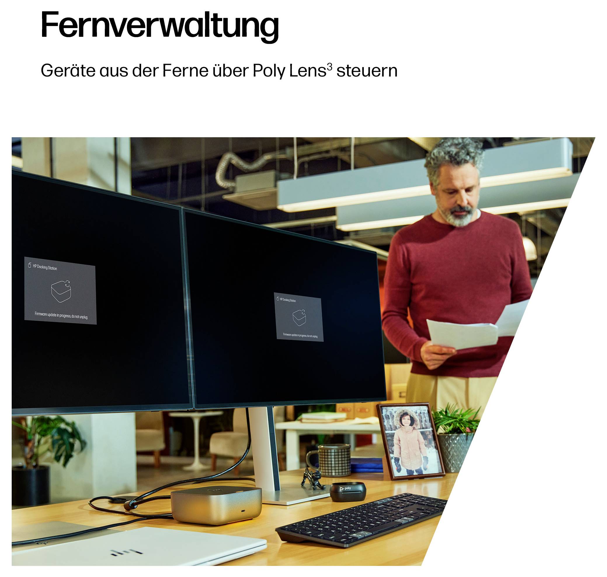 Mann im roten Pullover überprüft Papiere am Schreibtisch mit zwei Monitoren. Die Monitore zeigen die „Poly Lens