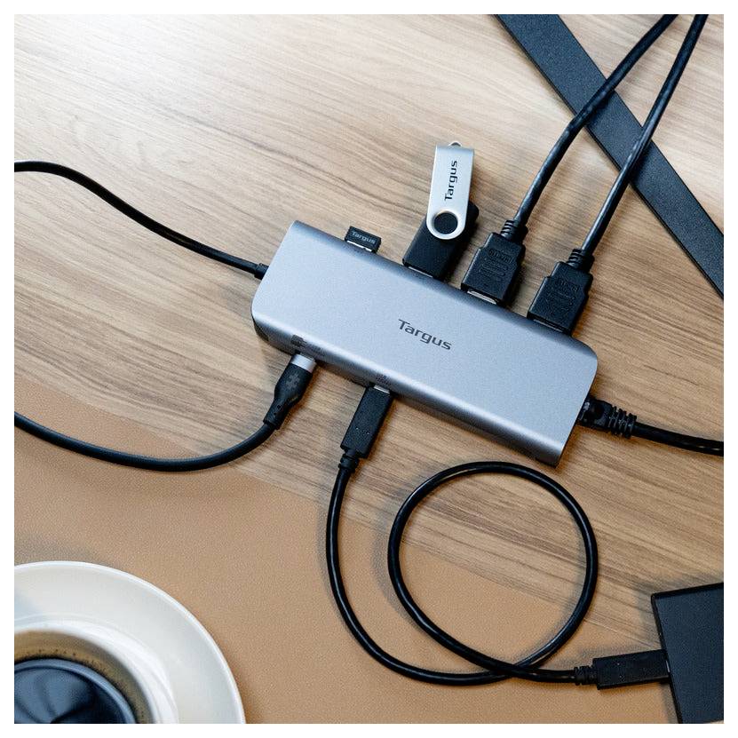 Ein USB-Hub mit mehreren Anschlüssen auf einem Holzschreibtisch, verbunden mit mehreren Kabeln und einem USB-Laufwerk, das die Gerätekonnektivität ermöglicht.