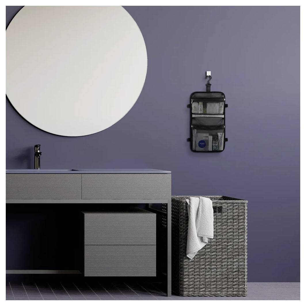 Modernes Badezimmermöbel mit Waschbecken, rundem Spiegel, Wandorganizer und Weidenkorb für Wäsche vor einer lila Wand.