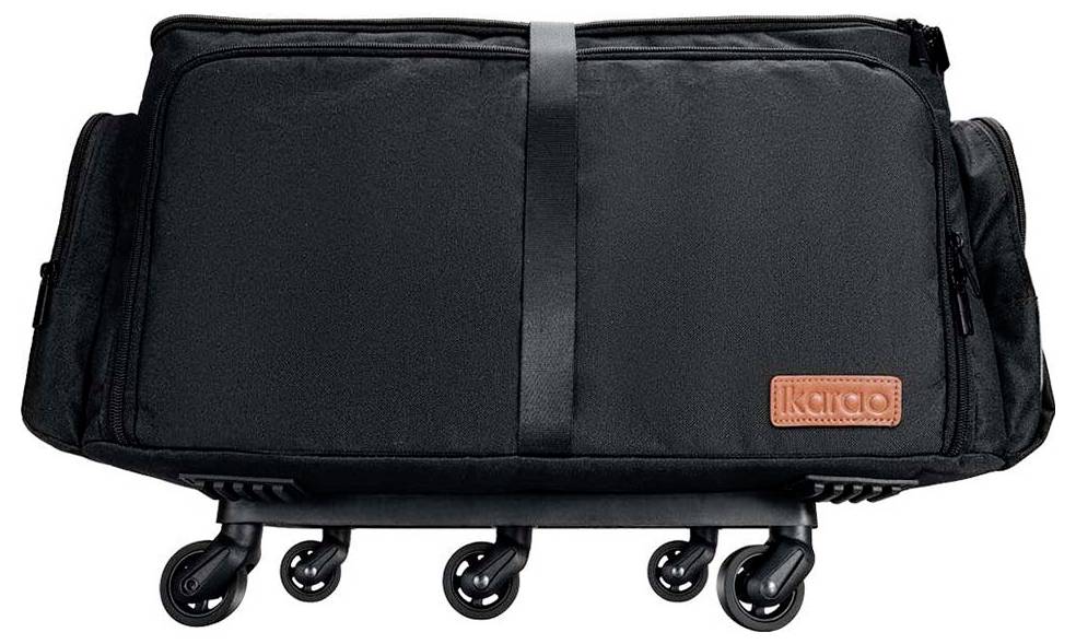 Schwarzer rollbarer Koffer mit mehreren kleinen Räderstützen, versehen mit einem Lederanhänger in Braun mit der Aufschrift 'ikado'.