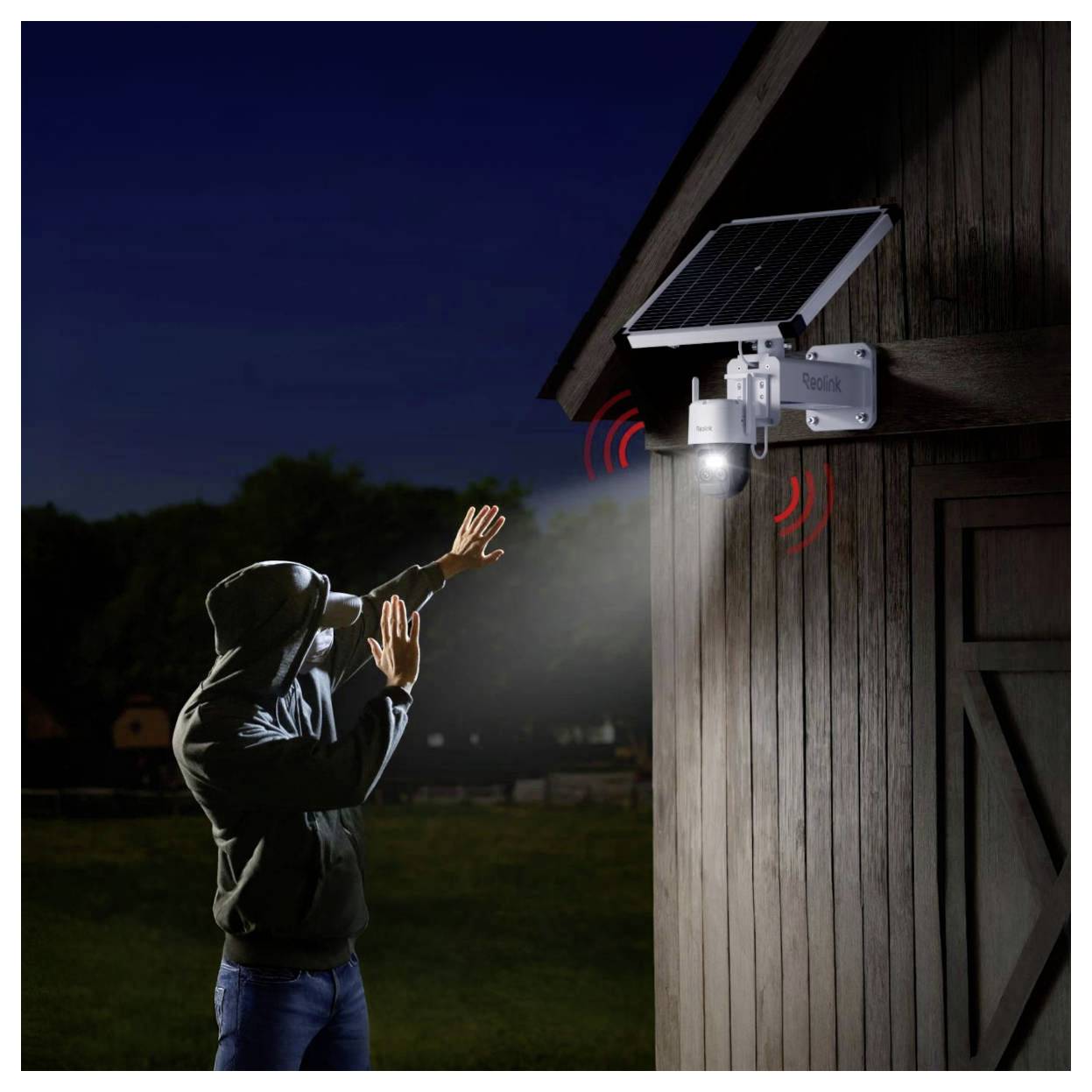 Eine Person, die nachts außen in der Nähe einer Scheune steht, wird vom Scheinwerfer eines aktivierten Bewegungsmelder-Sicherheitslichts erfasst und hebt die Sicherheit hervor.