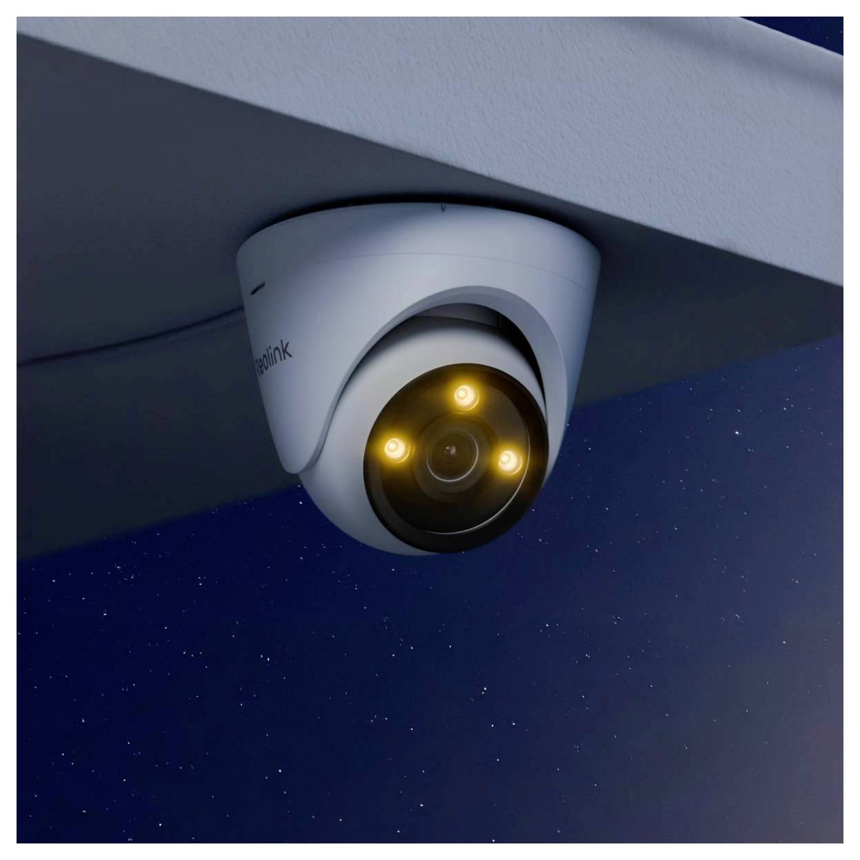 Eine Überwachungskamera mit vier leuchtenden Lichtern ist unter einer Dachkante angebracht und blickt nachts nach unten.