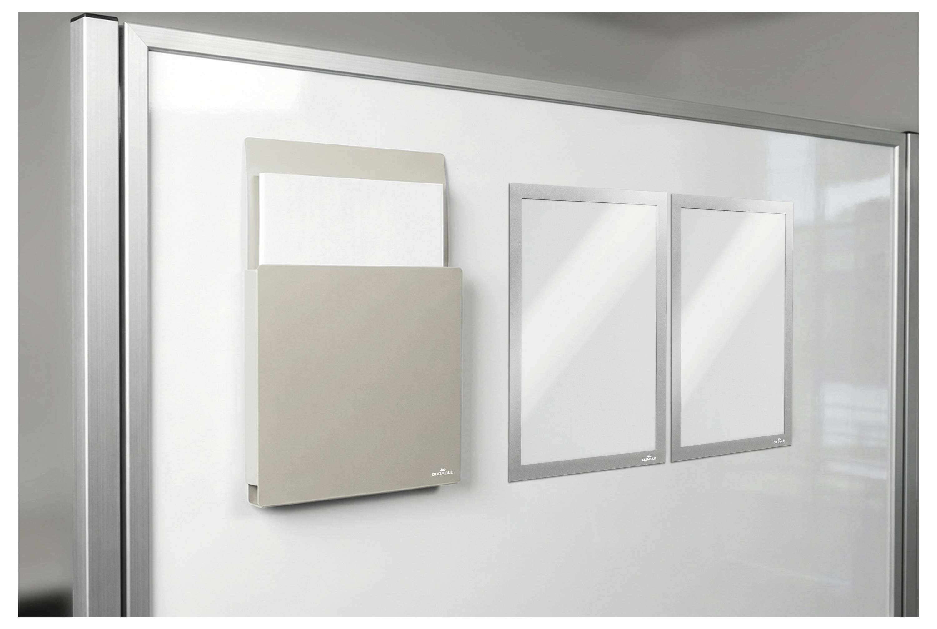 Ein magnetisches Wandpaneel mit einer Dokumentenhalterung und zwei Schlitzen zur Anzeige von Papieren, montiert auf einem Whiteboard in einer Büroumgebung.