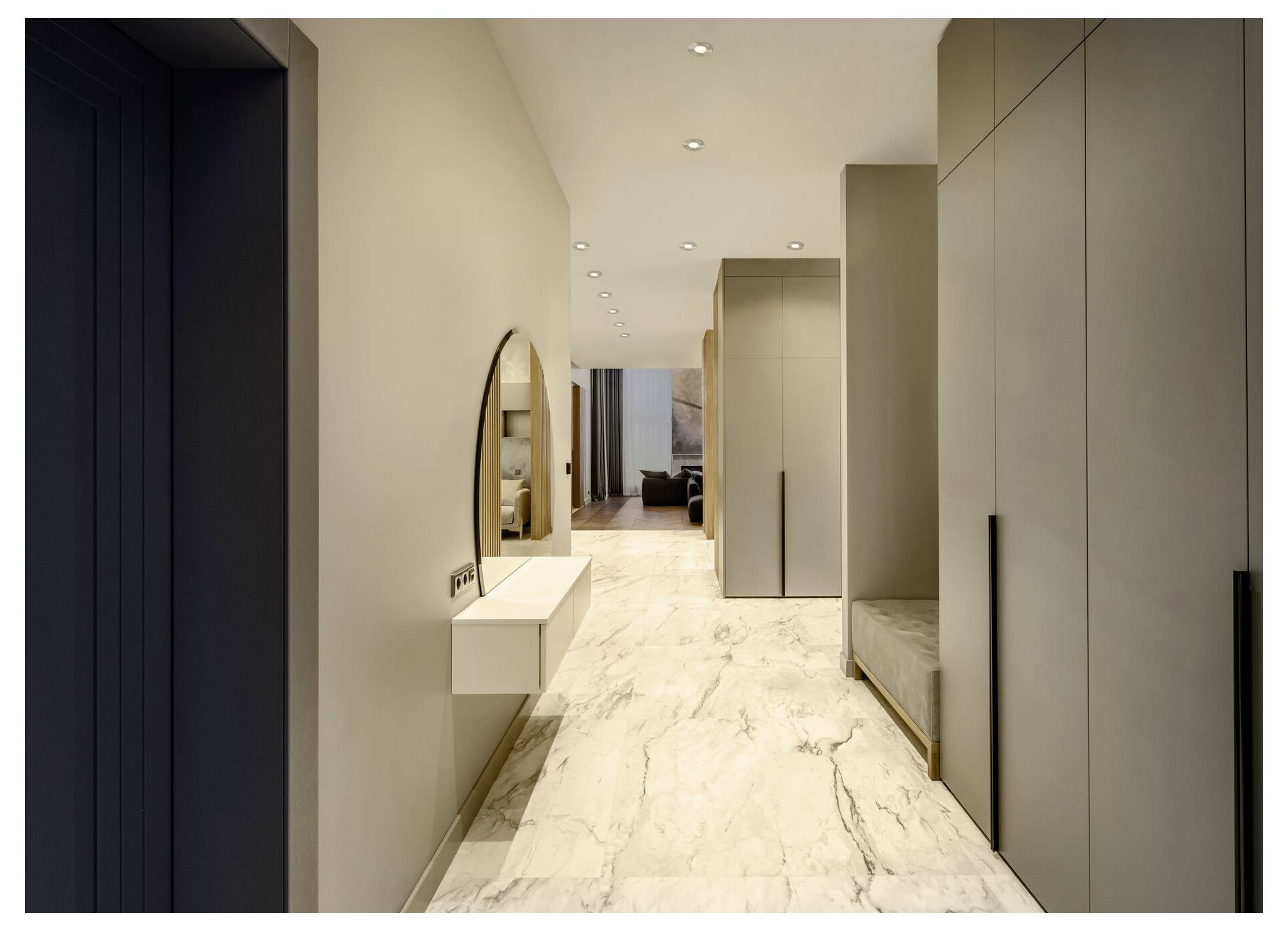 Ein moderner Flur mit Marmorboden, cremefarbenen Wänden, einem runden Spiegel und schlanken, raumhohen Schränken auf der rechten Seite.