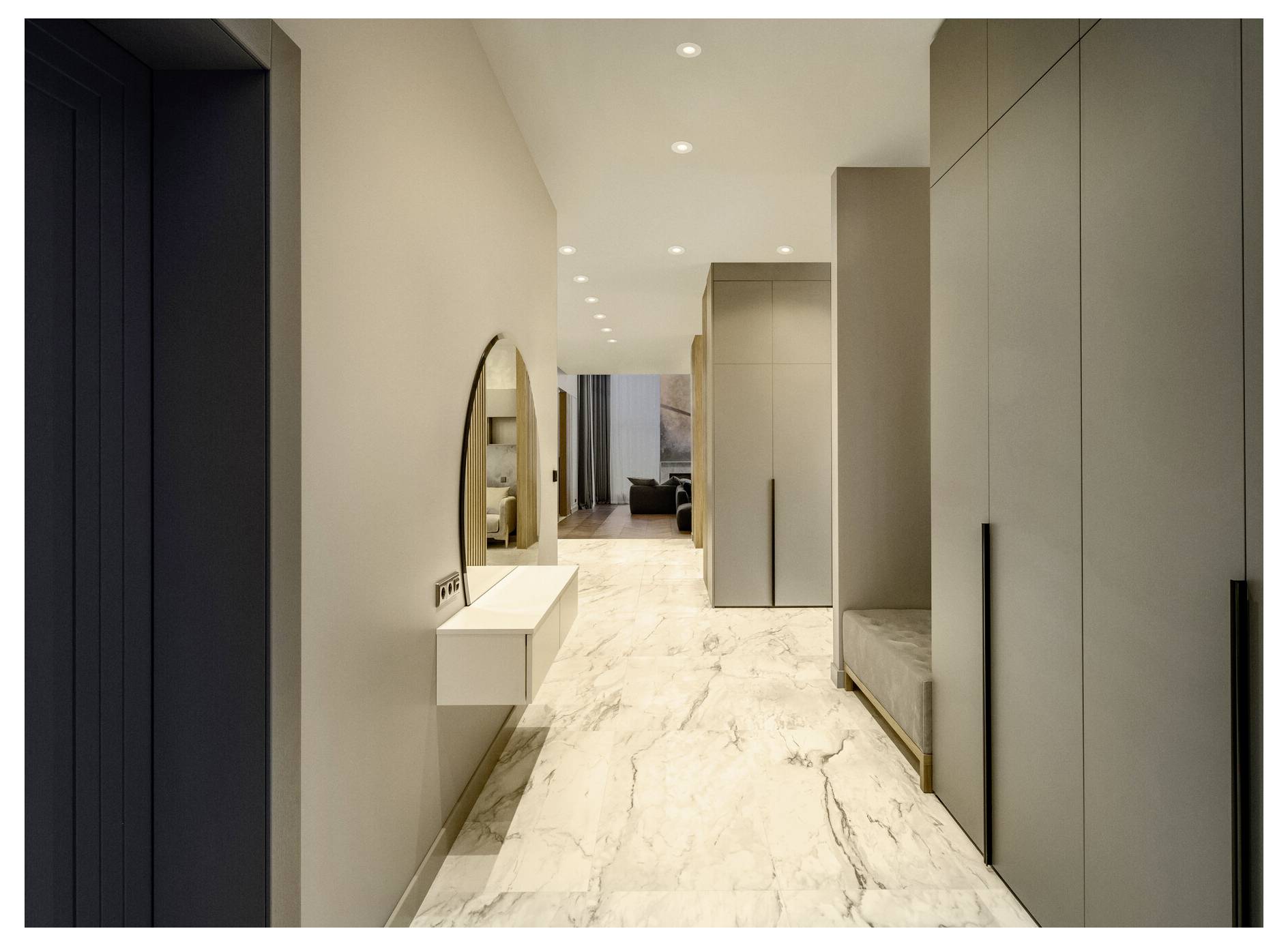 Ein moderner Flur mit Marmorboden, eingebauten Schränken, einem runden Spiegel über einem Konsolentisch und weicher Einbauleuchten, die zu einem Wohnbereich führen.
