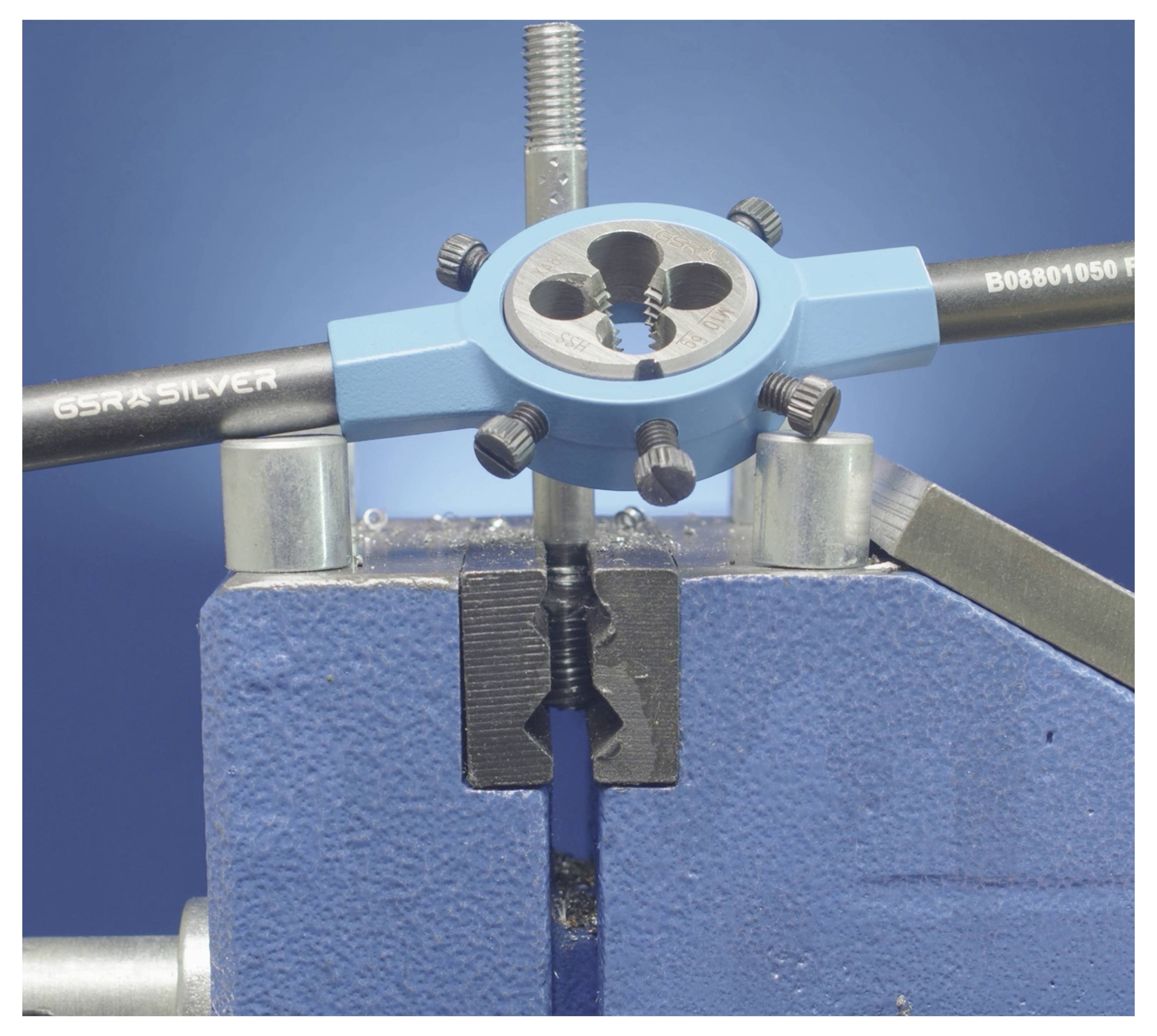 Ein Gewindeschneider und eine Schneideisen in einem Metallschraubstock ausgerichtet, ein Metallstab wird damit gewindeschneidend bearbeitet, vor blauem Hintergrund.