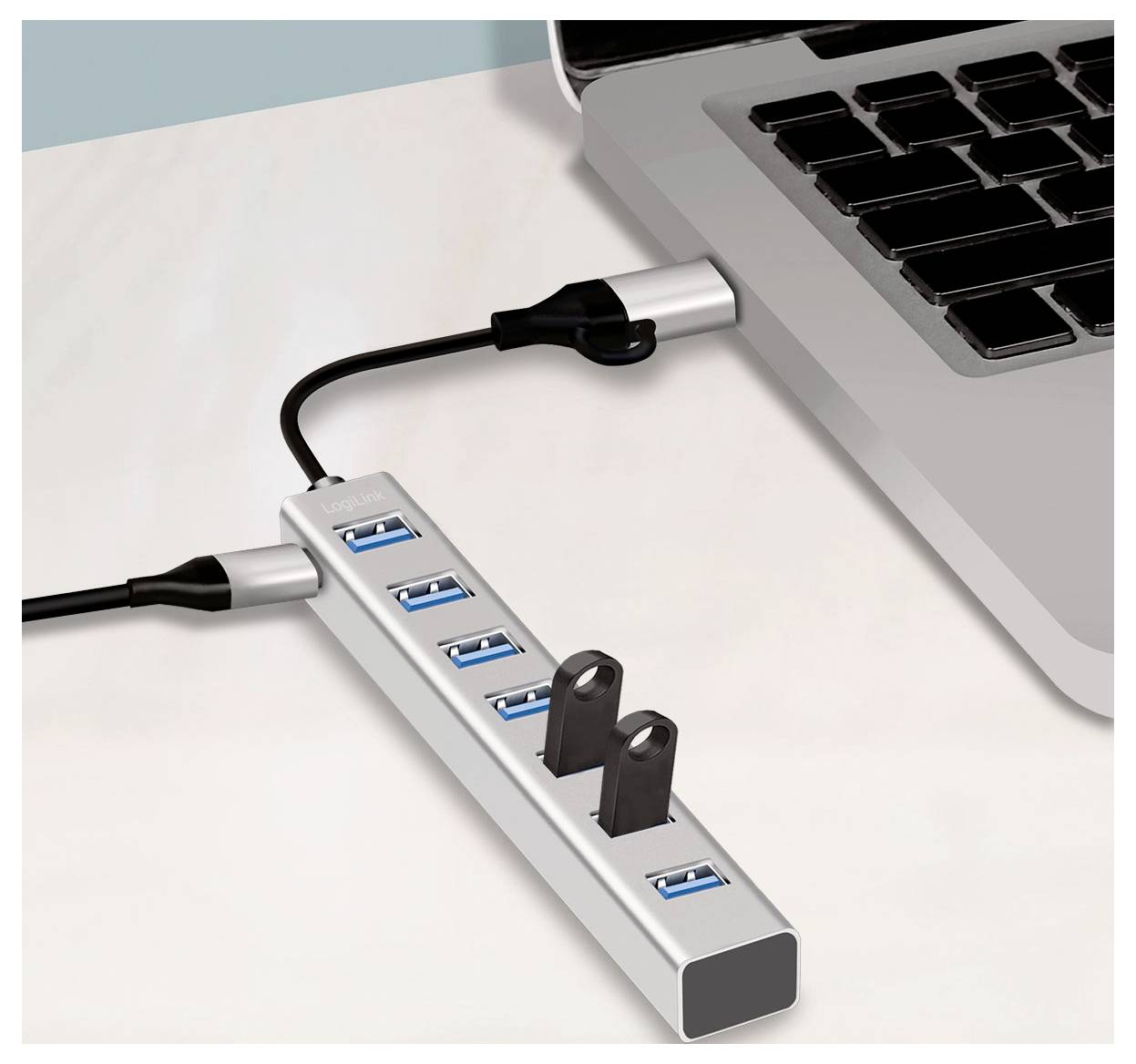 USB-Hub an einen Laptop angeschlossen, mit mehreren Anschlüssen und einer sichtbaren leeren Buchse auf einem Schreibtisch.