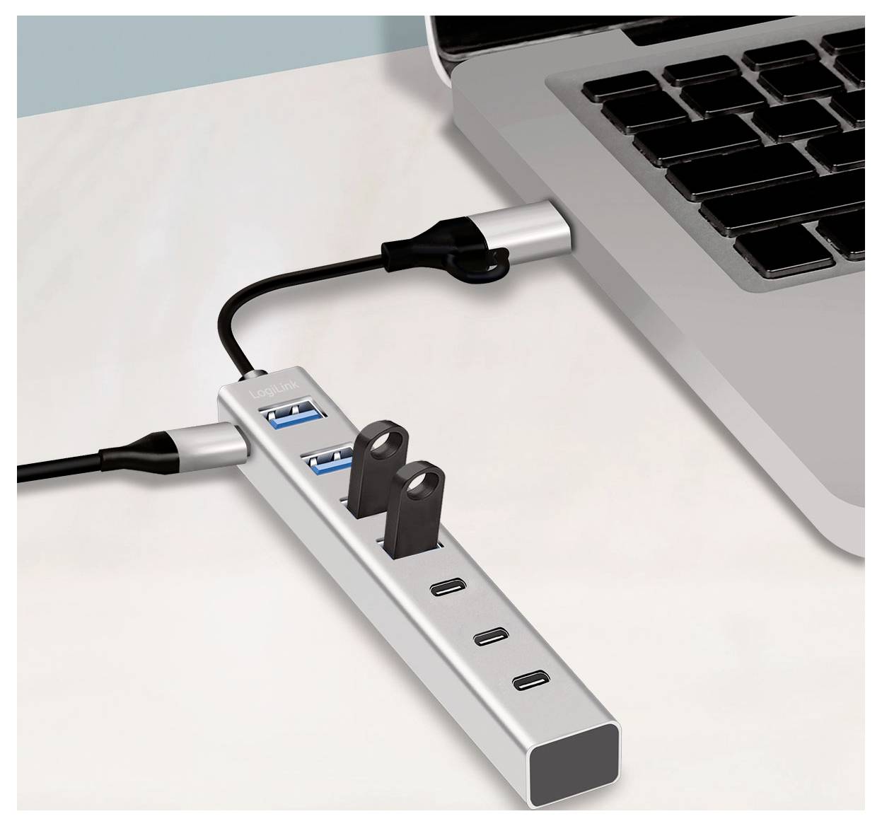 Laptop, der über einen USB-C-Hub mit mehreren USB-Anschlüssen und Stromkabel verbunden ist und erweiterte Konnektivität auf einem Schreibtisch zeigt.