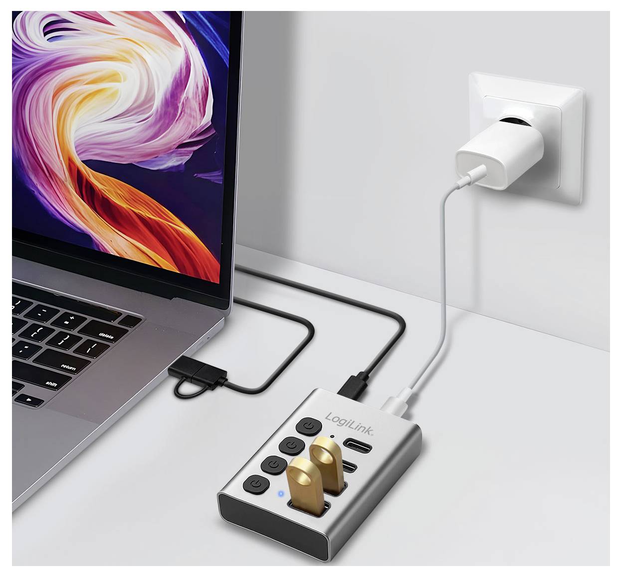 Laptop, das über einen USB-C-Hub/eine Steckerleiste an einer Wandsteckdose angeschlossen ist, mit zwei eingesteckten Kabeln und einem angeschlossenen Ladekabel.