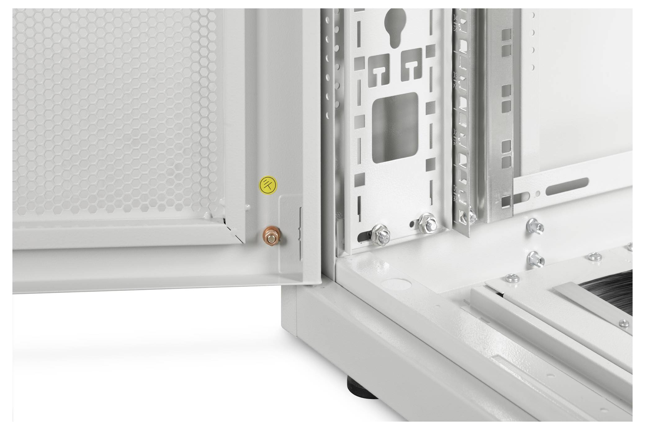 Nahaufnahme einer Metallschrankecke mit offener Tür, die ein gelochtes Panel und interne Schlitze für elektronische Komponenten zeigt.