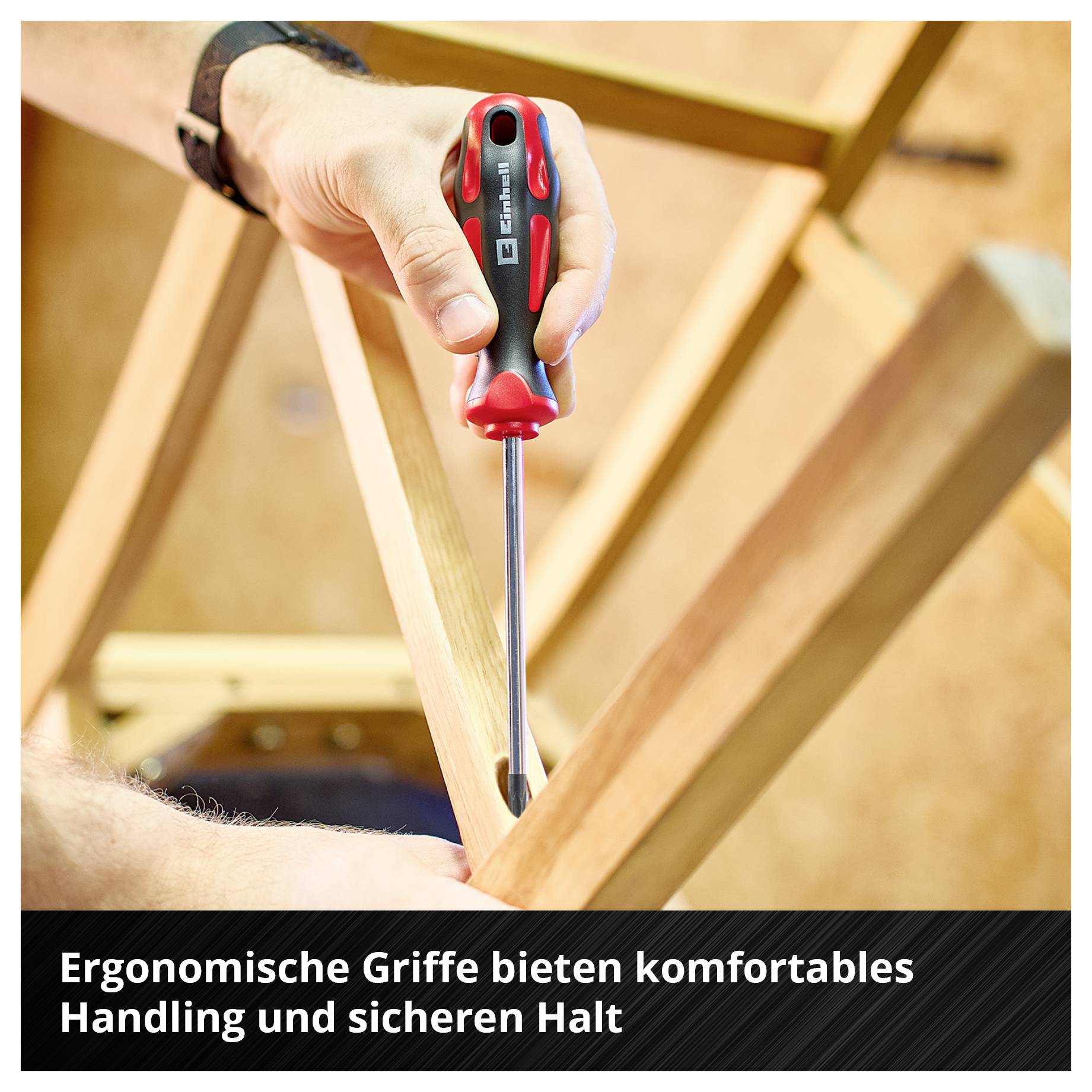 Hand mit Schraubendreher beim Arbeiten an einem Holzgestell; unten steht: 'Ergonomische Griffe bieten komfortables Handling und sicheren Halt'