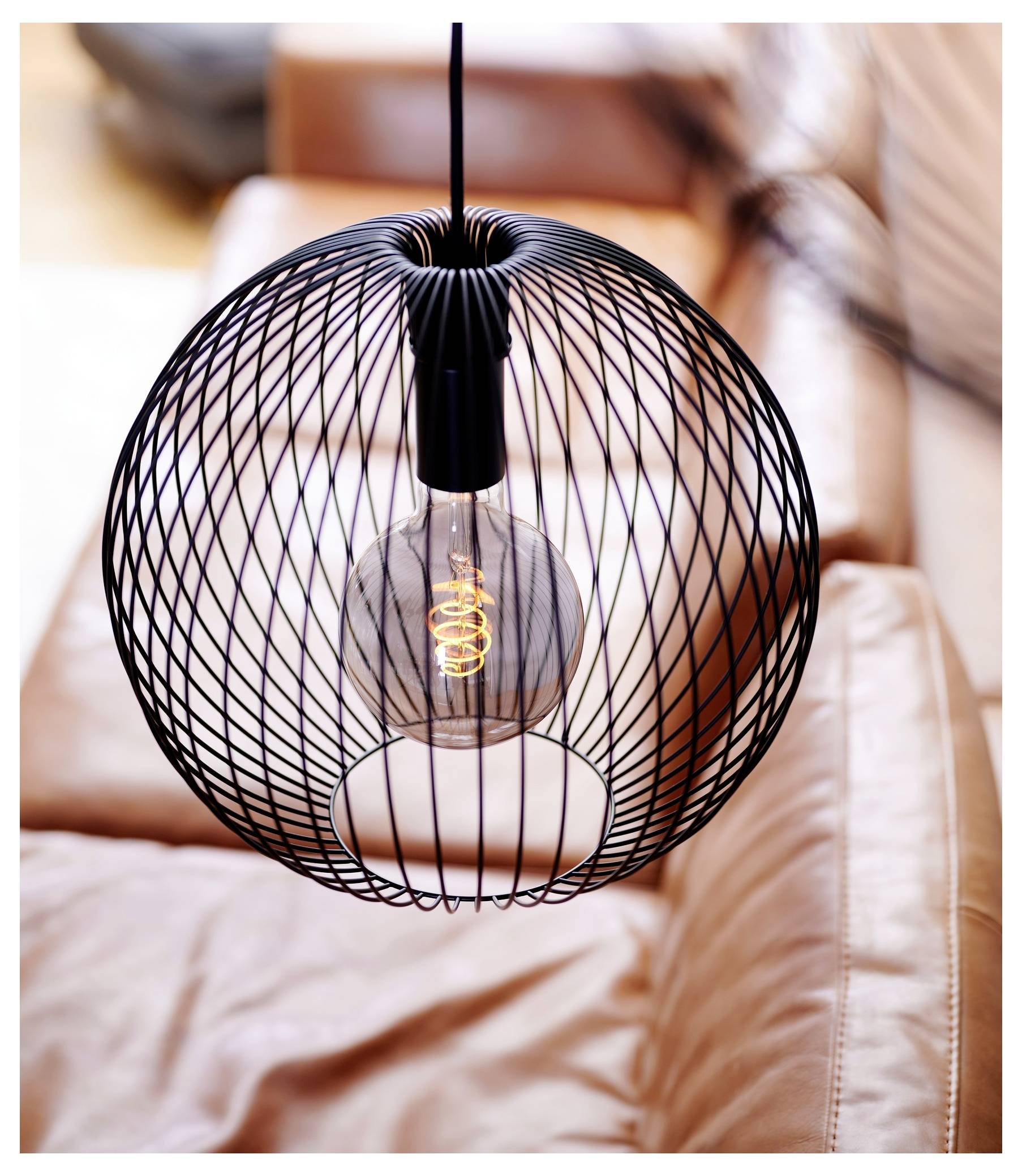 „Schwarze Draht-Pendelleuchte mit einer sichtbaren LED-Glühfadenbirne über einem braunen Ledersofa in einem modernen Wohnraum.
