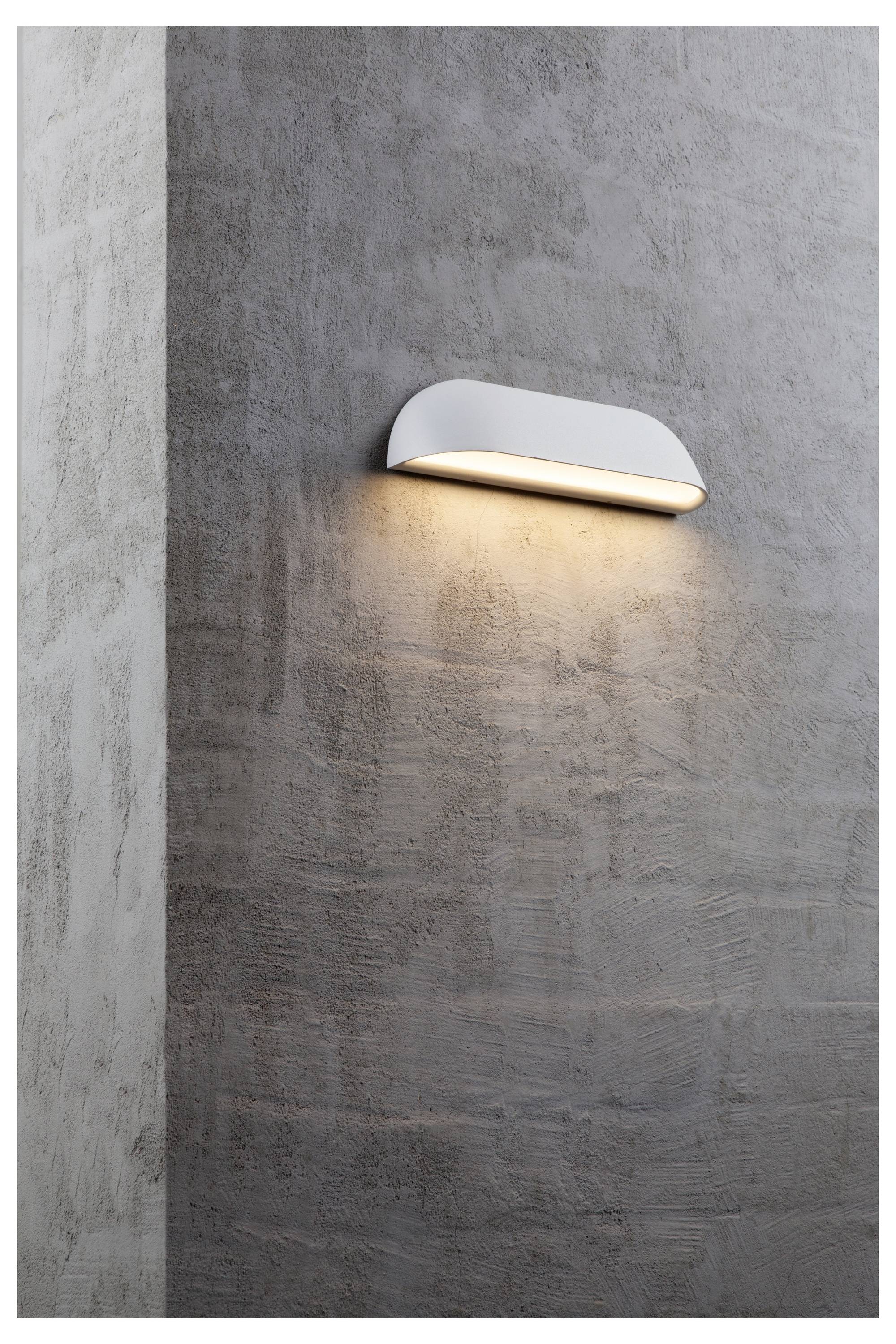 Eine moderne, gekrümmte Wandleuchte strahlt ein warmes Licht gegen eine strukturierte, graue Betonwand aus und schafft eine minimalistische und gemütliche Atmosphäre.