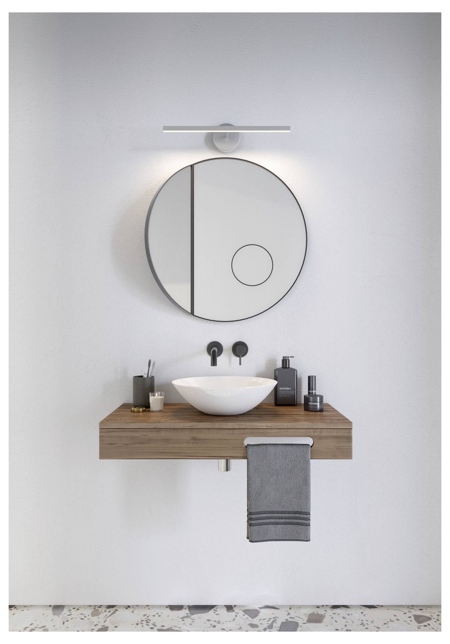 Ein modernes Badezimmer mit einem runden Spiegel über einem hölzernen Waschtisch. Ein weißes Waschbecken, schwarzer Wasserhahn und ordnungsgemäß angeordnete Toilettenartikel, mit einem grauen Handtuch darunter.