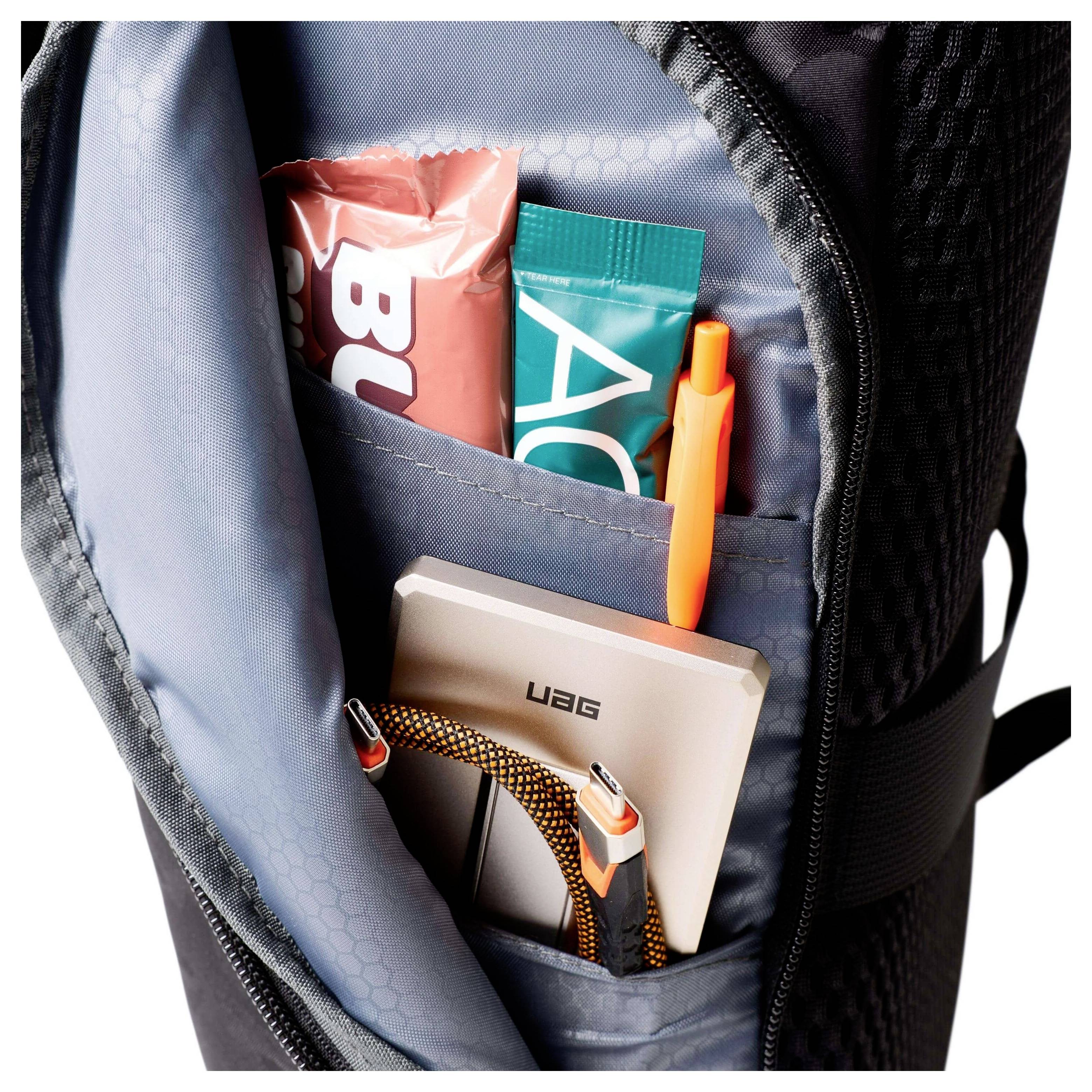 Öffnen Sie die Rückseite des Rucksacks, die zwei Energieriegel, einen orangefarbenen Stift, eine tragbare Festplatte und ein USB-Kabel enthält.