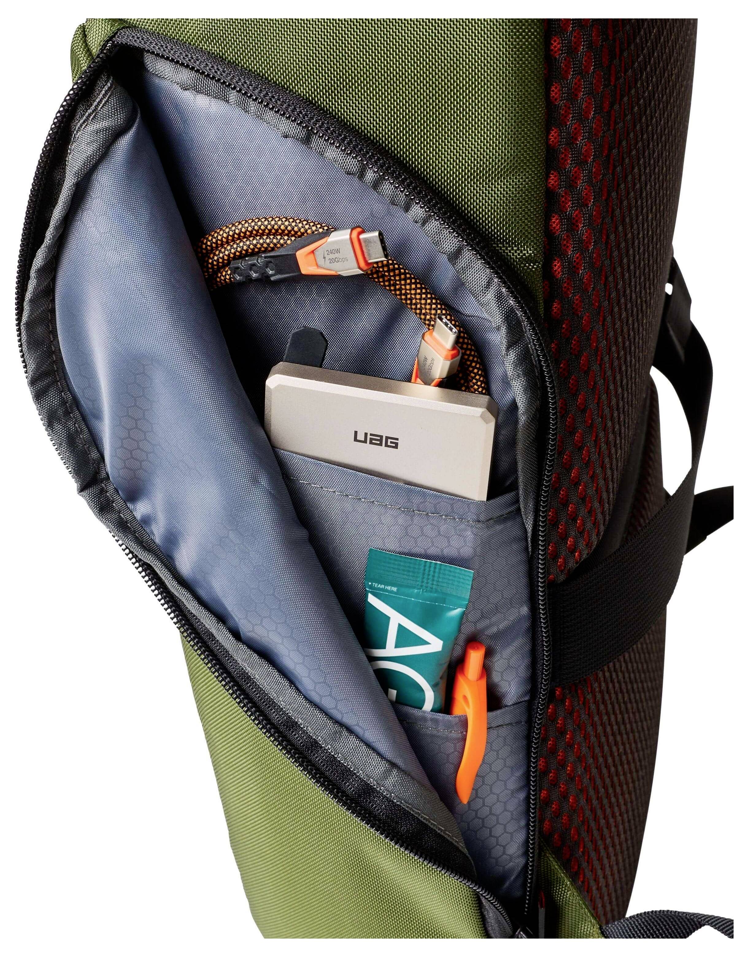 Eine offene Rucksacktasche zeigt ein USB-Kabel, ein UAG-Gerät und einen orangefarbenen Stift und hebt den organisierten Stauraum im Inneren hervor.