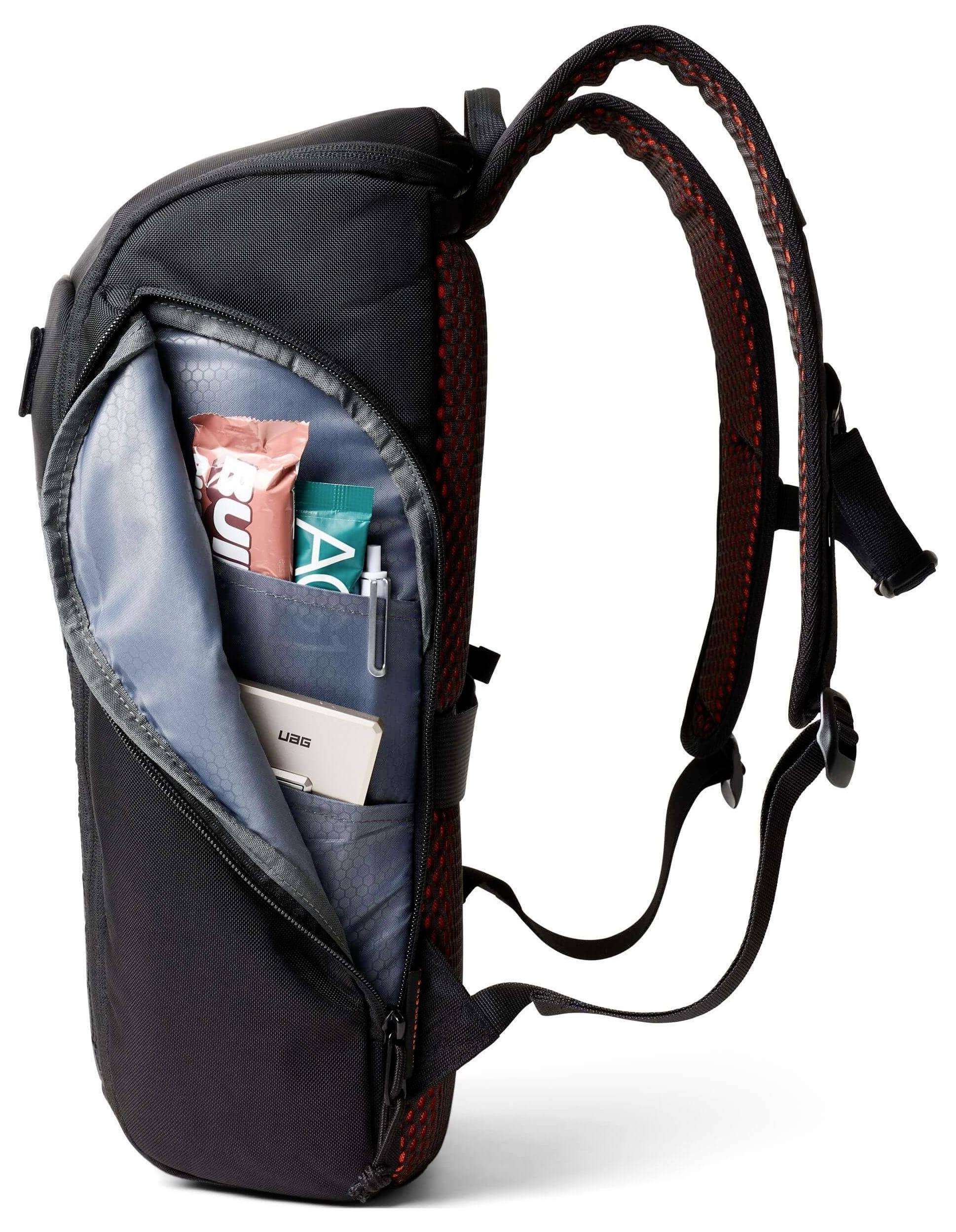 Ein schwarzer Rucksack mit einem offenen Fach zeigt Snacks, einen Stift und ein Telefon und demonstriert seine Speicherkapazität und Organisationsfunktionen.
