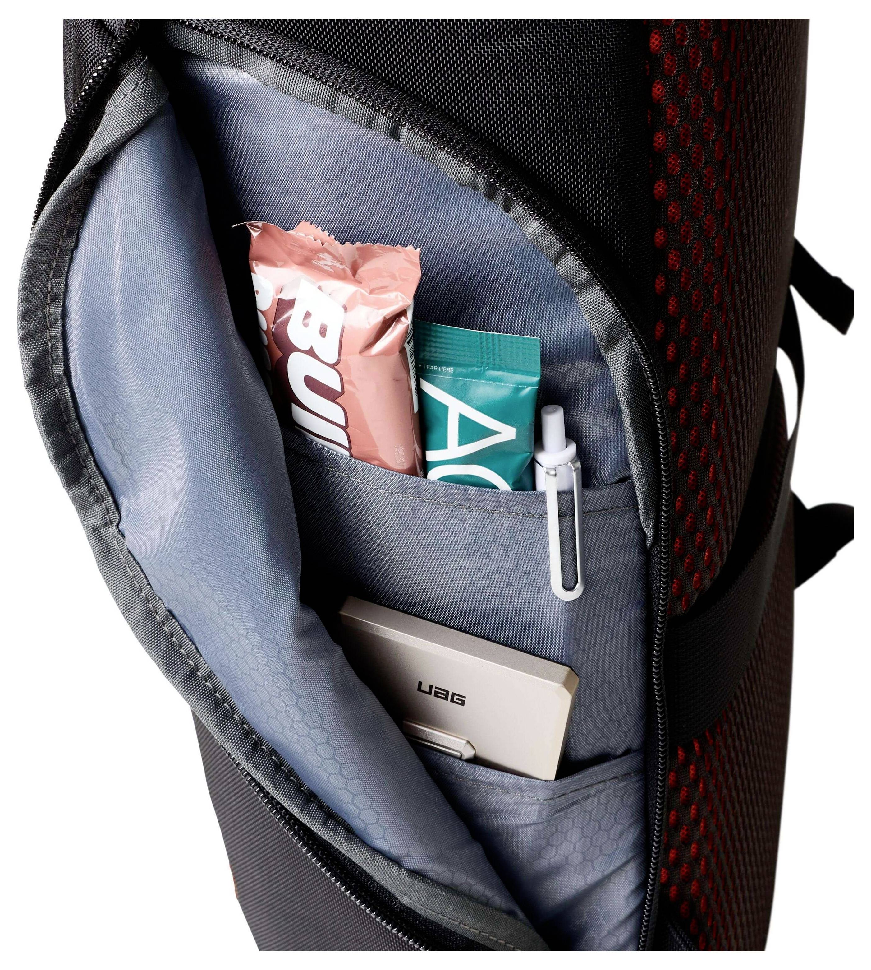 Eine Rucksacktasche mit Proteinriegeln, einem USB-Stick, einem Stift und einem blaugrünen Paket, die Organisation und Lagerverwaltung zeigt.