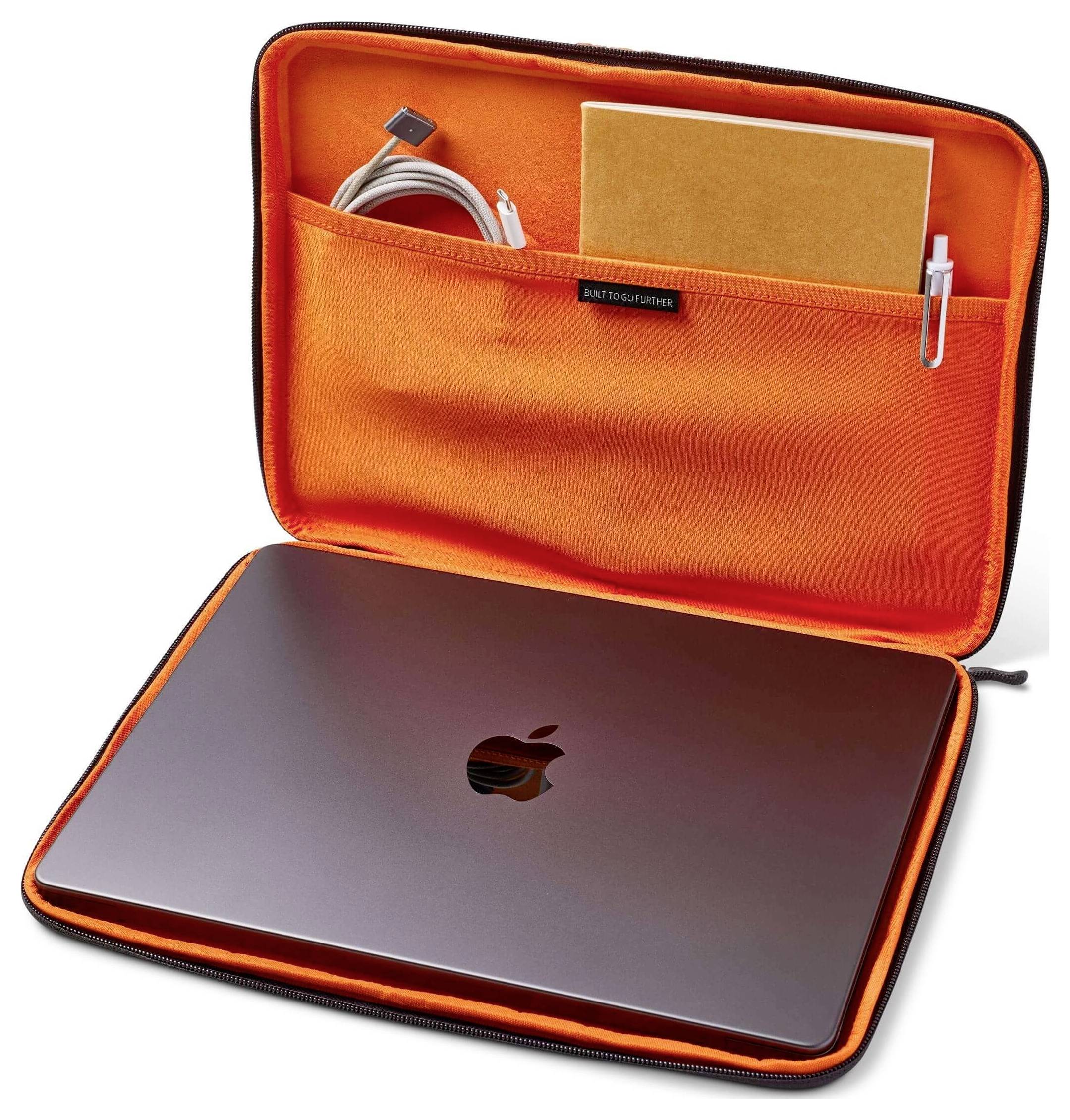 Ein Laptop in einer orangefarbenen Tasche mit Fächern, die ein Notizbuch, einen Stift und ein Kabel enthalten.