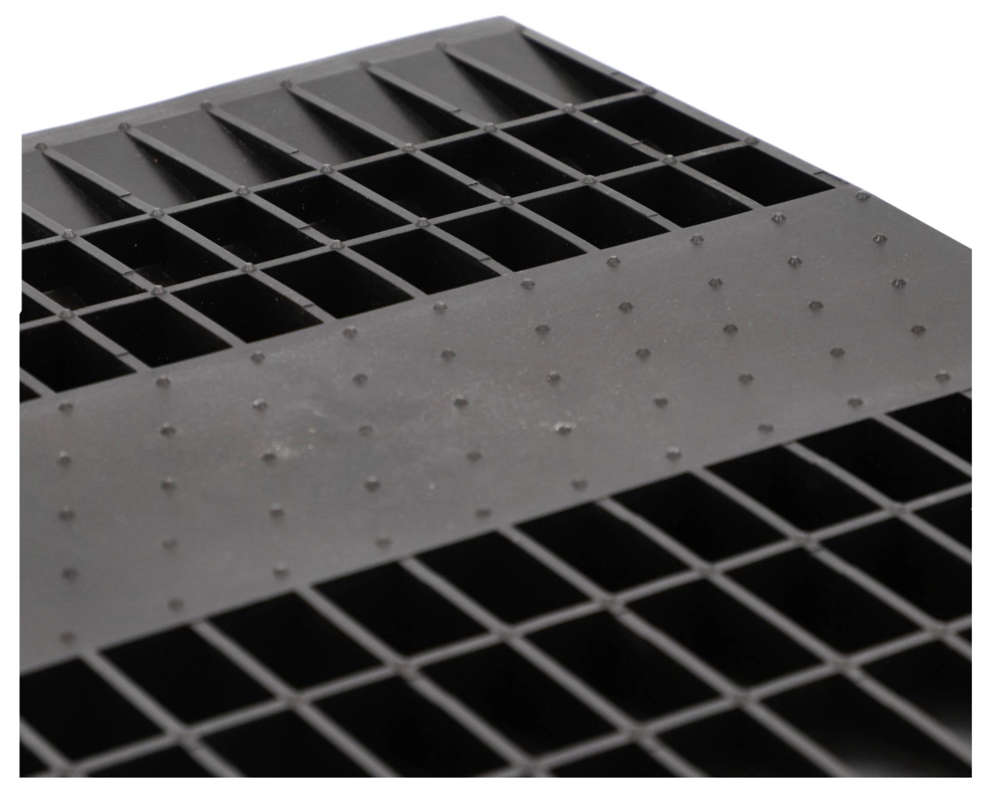 Eine Nahaufnahme einer schwarzen Kunststoffgitterstruktur mit rechteckigen Löchern.