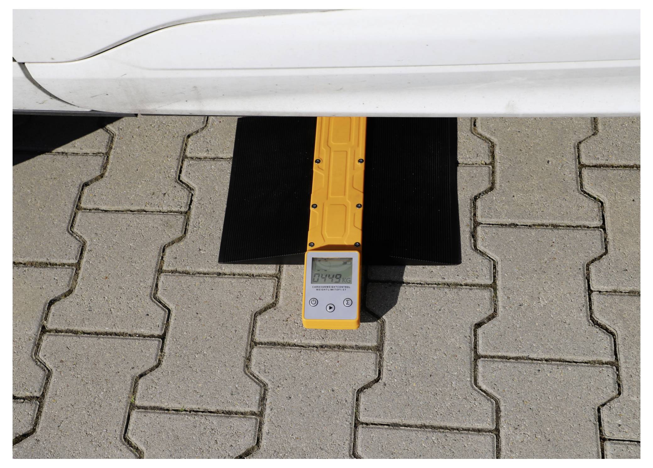 „Fahrzeug auf einer Auffahrtsrampe mit digitalem Display, das 1137 kg anzeigt und eine Gewichtsmessung angibt. Das Gerät ist gelb und unter dem Fahrzeug positioniert.