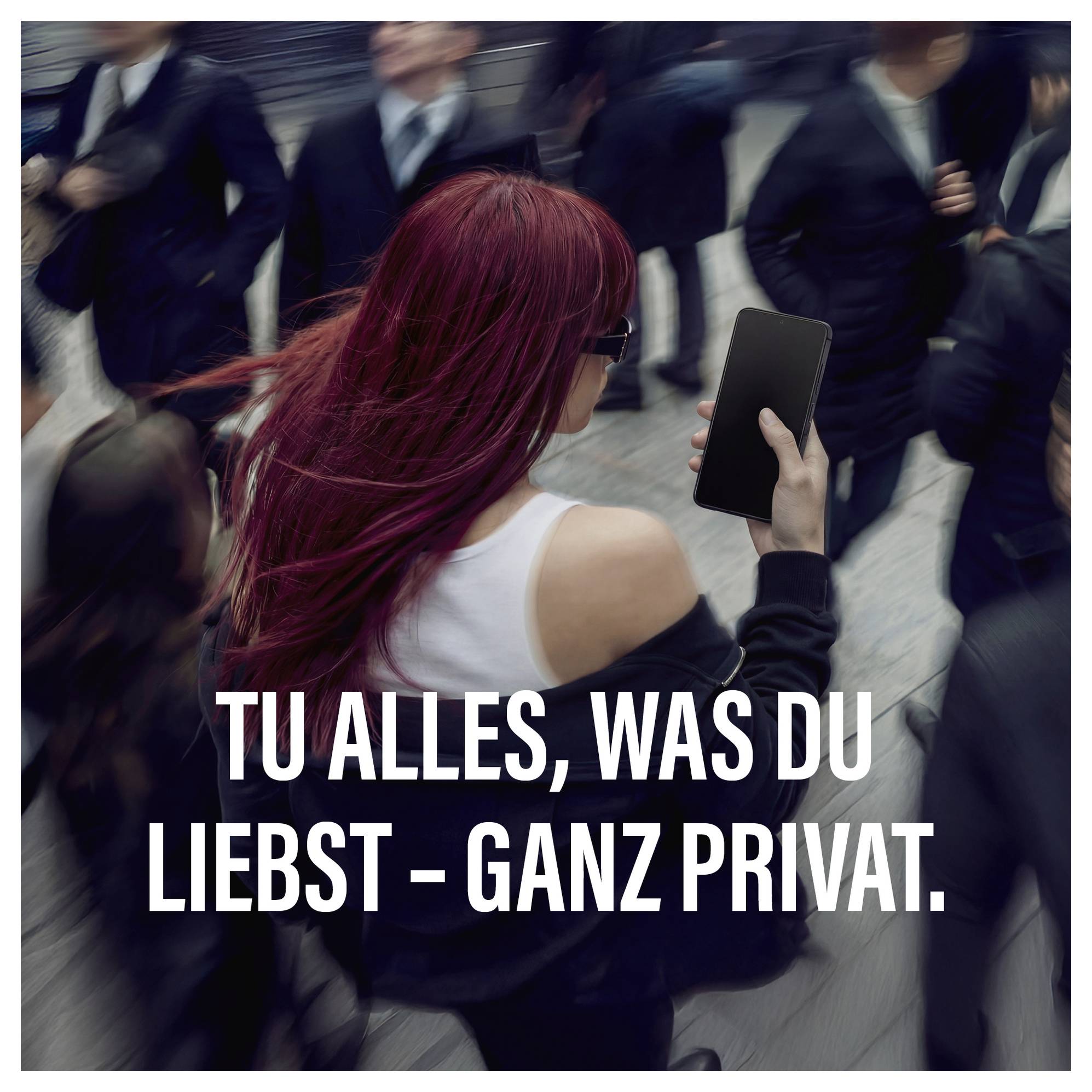 Eine Frau mit roten Haaren benutzt ein Smartphone, während sie in einer belebten Menschenmenge geht. Der deutsche Text lautet: „Tu alles, was du liebst - ganz privat.