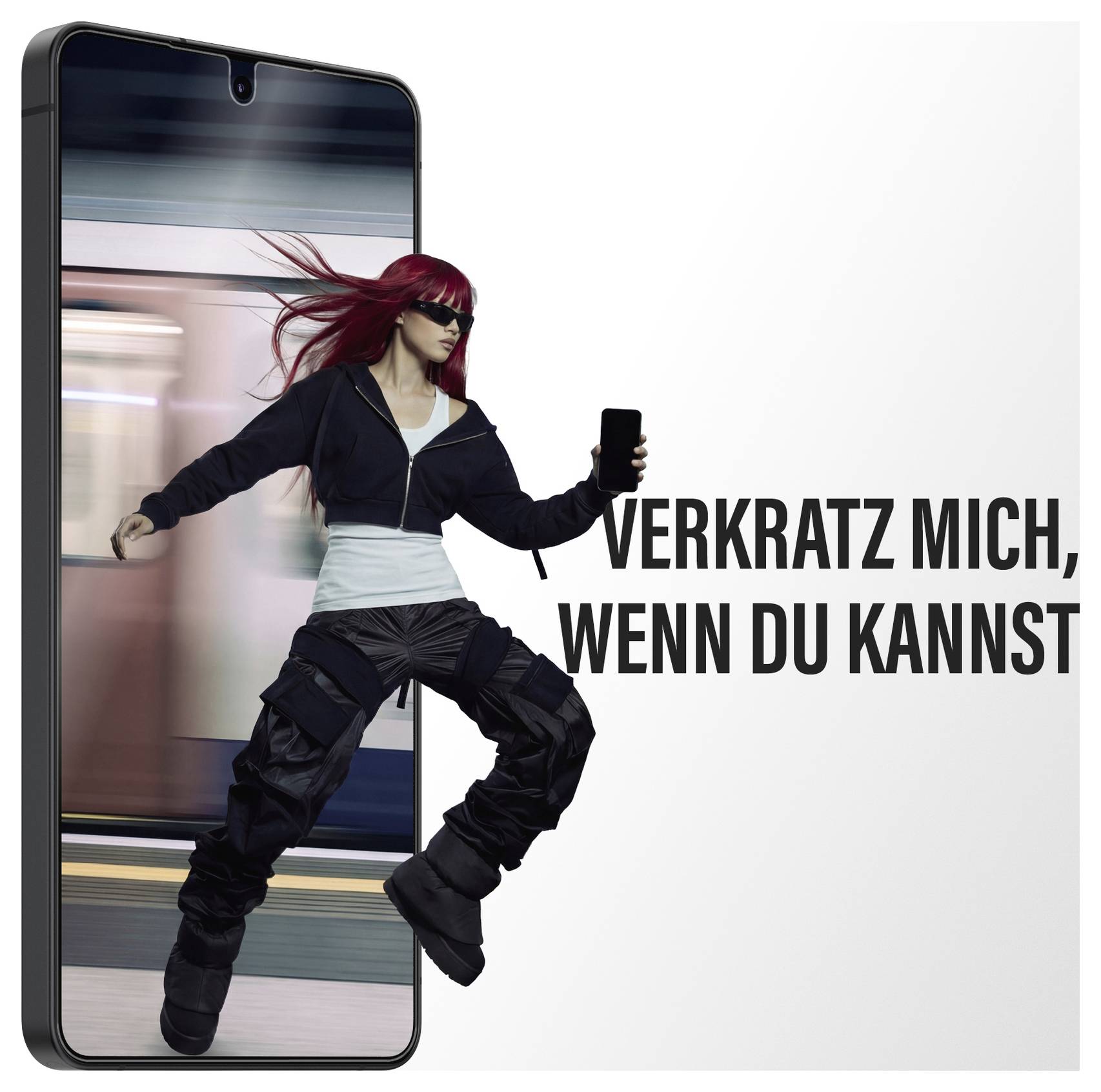 Ein Telefon zeigt eine Frau, die durch einen Bahnhof läuft. Der deutsche Text lautet „Verkratz mich, wenn du kannst