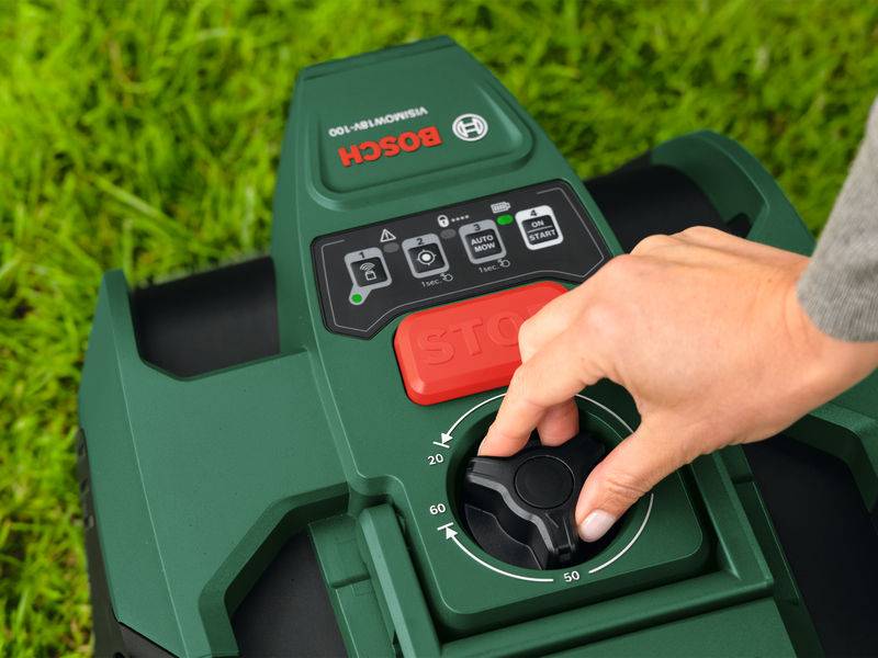 »Bosch« Roboter-Rasenmäher-Bedienfeld mit einer Hand, die am Drehregler verstellt wird. Das Bedienfeld verfügt über Tasten für Stopp, Start und weitere Funktionen.
