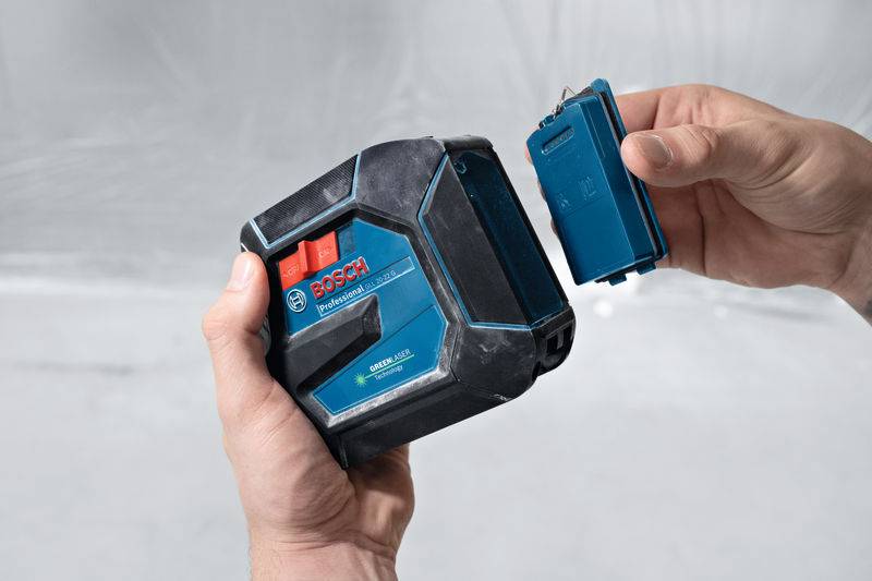 Eine Person hält ein Bosch-Laser-Messgerat mit austauschbarem Akku in der Hand und demonstriert den Einschub des Akkus.