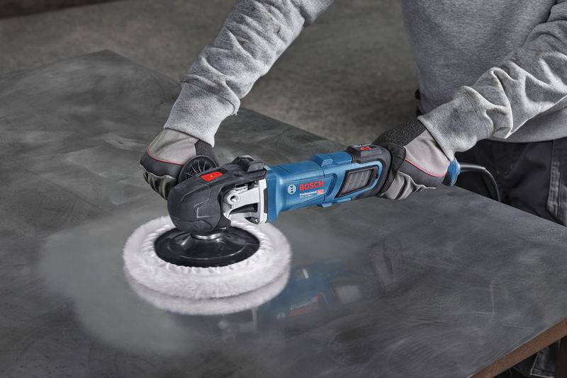 Eine Person, die einen Bosch-Poliermaschine auf einer Metalloberfläche verwendet, trägt Handschuhe und ein langärmliges graues Hemd zum Schutz.