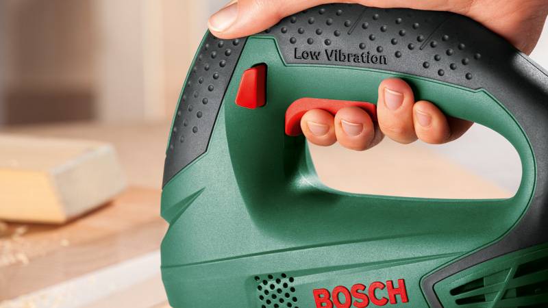 Eine Hand hält eine grüne Bosch-Stichsäge mit der Aufschrift 