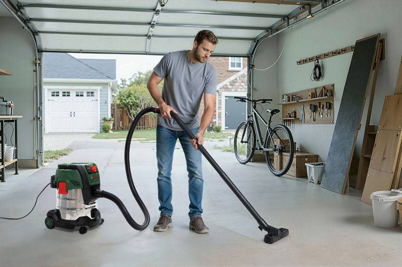 Eine Person reinigt einen Garagenboden mit einem Staubsauger. Die Garage ist organisiert mit Werkzeugen an der Wand und einem Fahrrad in der Nähe.