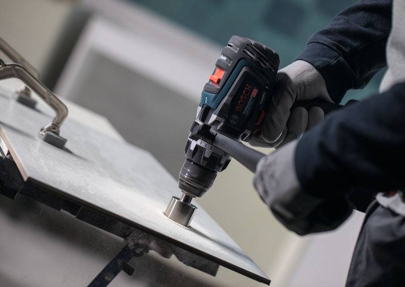 Eine Person verwendet eine Elektrobohrmaschine mit einer kreisförmigen Aufsatzvorrichtung, um ein Loch in ein Metallblech zu schneiden und zeigt dabei präzise Maschinenarbeit.