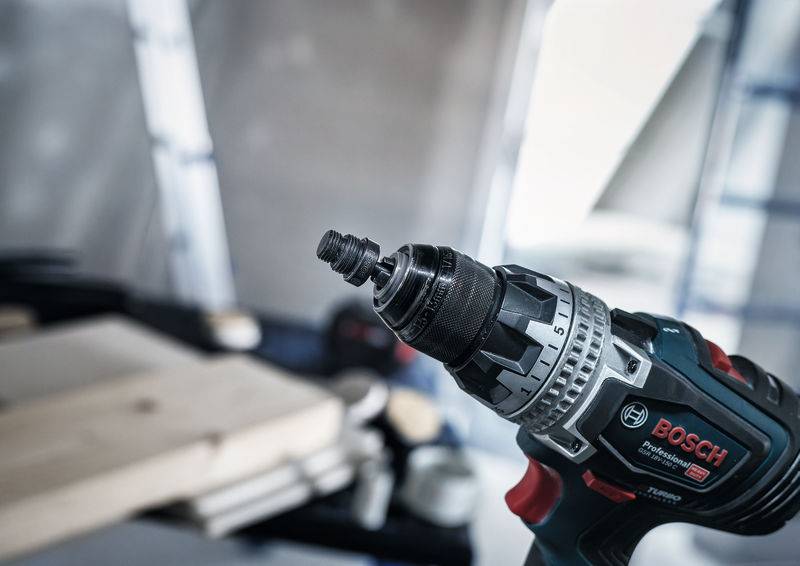 Eine Nahaufnahme einer Elektrobohrmaschine in einer Werkstattwerkstatt, mit Fokus auf den Bohraufsatz. Der Arbeitsbereich im Hintergrund ist verschwommen.