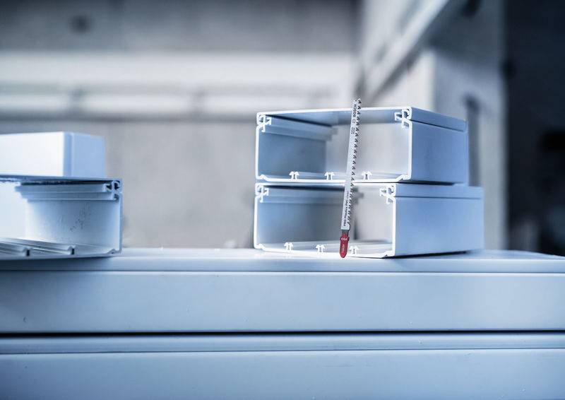 Zwei übereinander gestapelte weiße Metallrahmen mit einem Messstab, auf einer Oberfläche in einer Werkstattumgebung platziert.