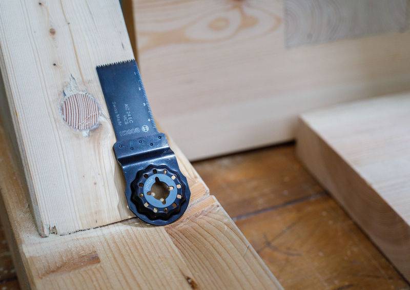 Eine Sägeklinge, die an einer Holzoberfläche in einer Holzbearbeitungsumgebung befestigt ist. Die Klinge ist Teil eines Werkzeugs, das auf einer Holzwerkbank ruht.