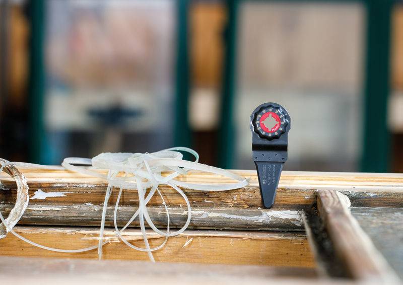 Eine Holzoberfläche mit einer roten und schwarzen Skala, die hineingesägt ist, umgeben von Drähten und Klebematerialien in einer Werkstattumgebung.