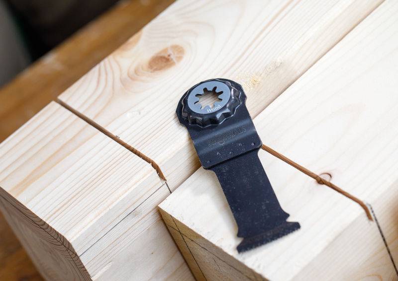 Eine Nahaufnahme eines Metallsägeblattes, das auf zwei Holzbalken mit frischen Schnitten liegt und zeigt, dass Holzarbeiten im Gange sind.