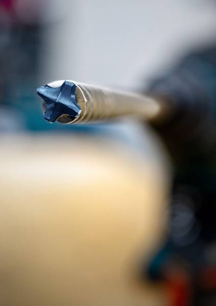 Nahaufnahme eines metallischen Bohrers im Fokus mit verschwommenem Hintergrund; vermittelt Präzision und industrielle Werkzeugnutzung.