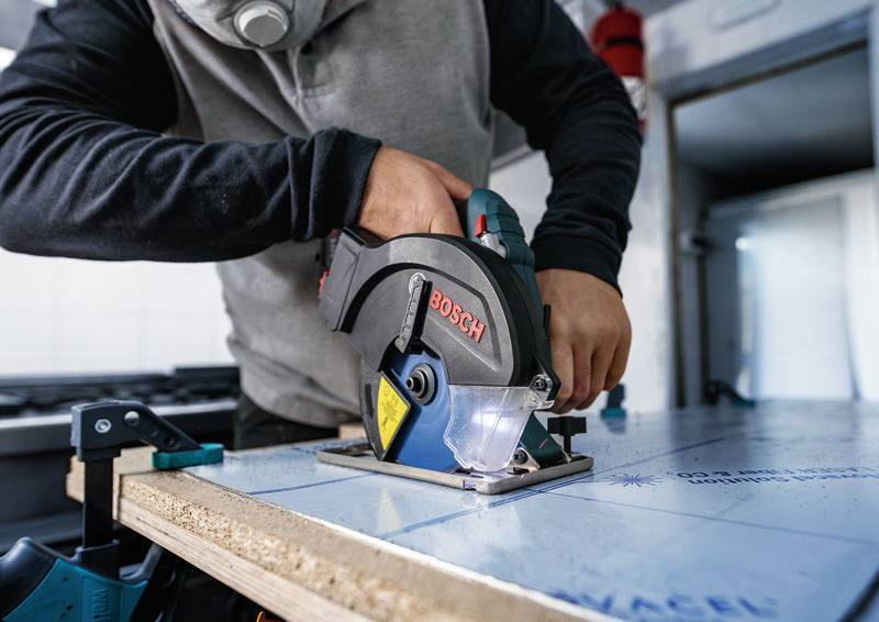 Eine Person benutzt eine Bosch-Kreissäge, um ein Stück Holz zu schneiden, und zeigt dabei eine Werkstattumgebung, die sich auf Holzbearbeitung und Handwerkskunst konzentriert.