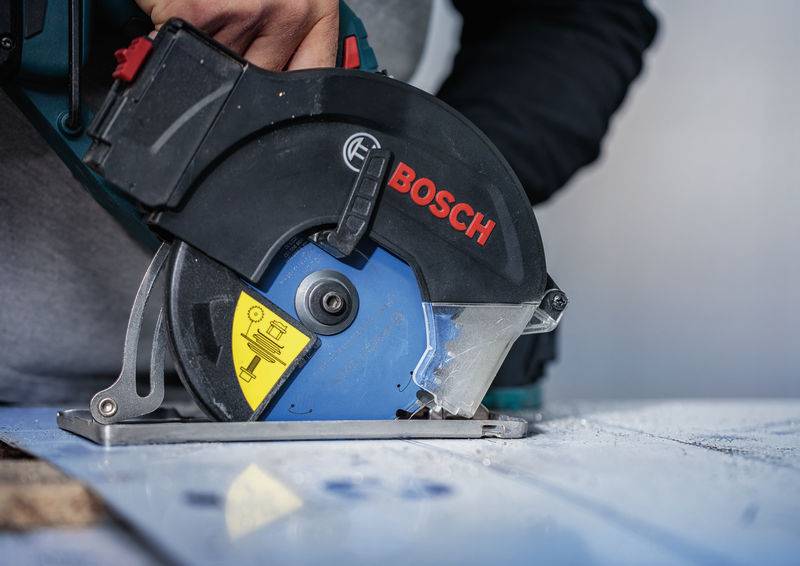 Eine Person nutzt eine Bosch-Kreissäge, um ein Stück helles Holz zu schneiden, wobei der Fokus auf Präzision und Kontrolle liegt.